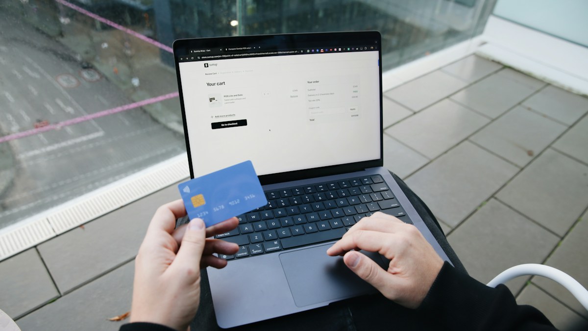 Pessoa com notebook e cartão de crédito planejando como economizar na Black Friday